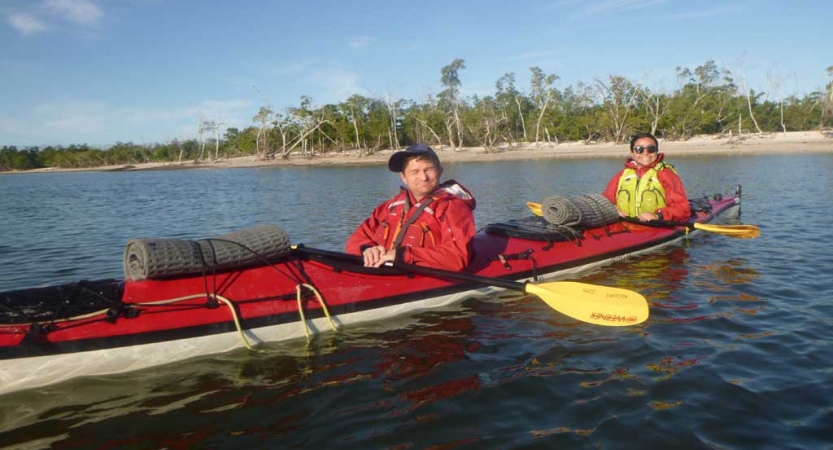 Two people sitting inside a red kayak smile for the photo. 